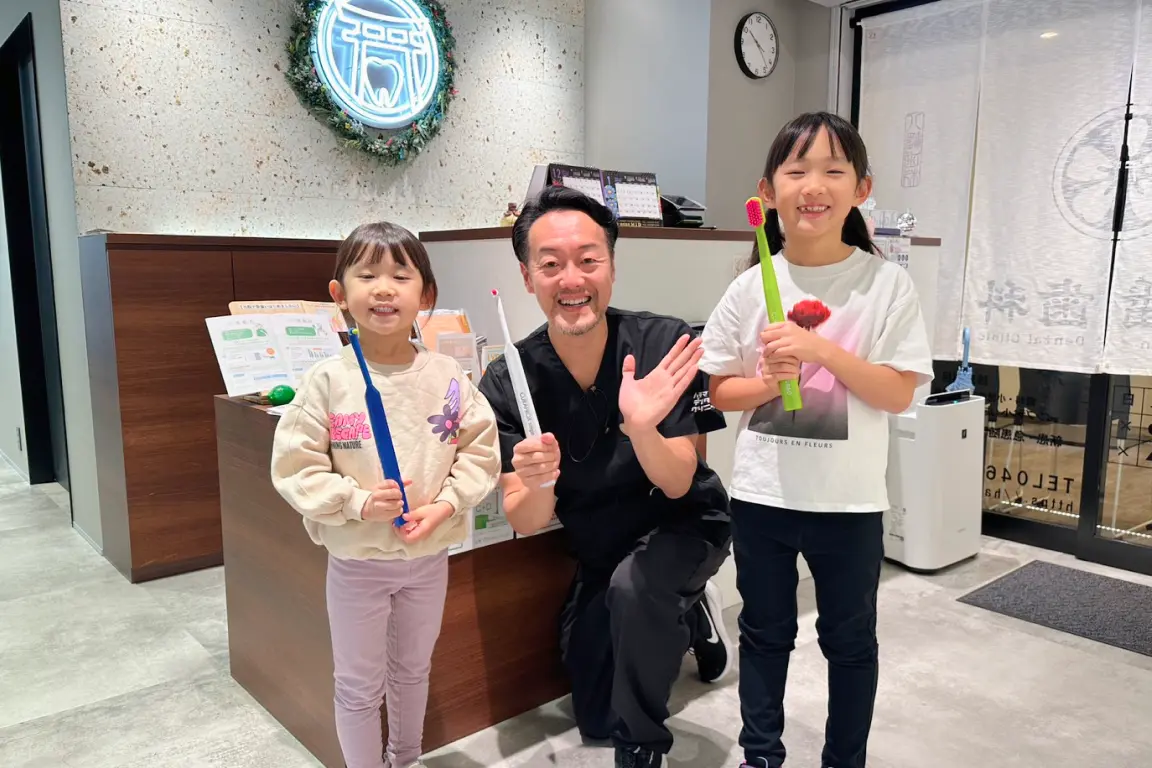 笑顔の子どもとハチマンデンタルクリニックの歯科医師